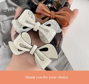 Detailed close-up of bow hair ties in cream lace and amber acetate finishes