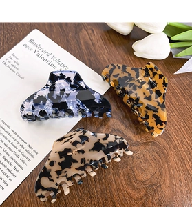 Detailed close-up of three large acetate hair claws with leopard and marble patterns