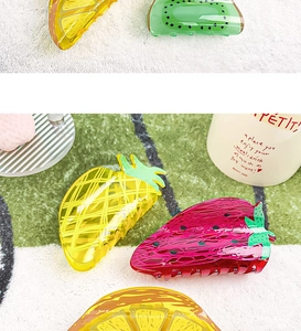 Detailed view of colorful acrylic fruit hair claws in strawberry and lemon shapes