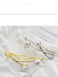 Detailed view of baroque pearl hair clips in gold and silver finish on white background