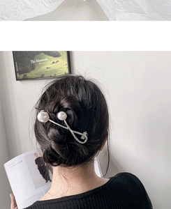 Detail of silver twisted hair clip with white baroque pearls on elegant bun hairstyle