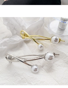 Detailed macro view of gold and silver baroque pearl hair clips with metallic wavy design
