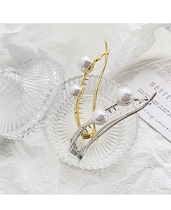 Detailed view of baroque pearl hair clips in gold and silver finish on glass tray