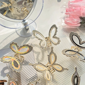 Elegant gold butterfly hair claw clip with rhinestones and pearl white finish in a mirror view