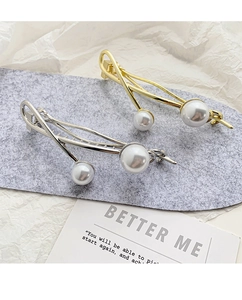 Detailed view of elegant gold and silver hair clips with baroque pearls on a grey mat