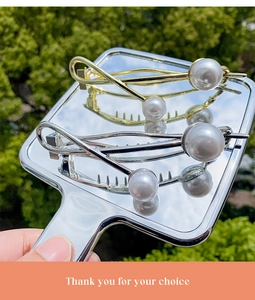 Close-up of sleek gold and silver hair clips with large white baroque pearls