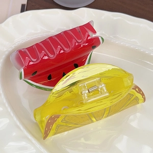Watermelon and lemon acrylic fruit hair claws displayed on a white ceramic plate