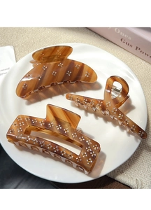 Detail of tortoise shell claw clips set with rhinestone flowers on a ceramic plate
