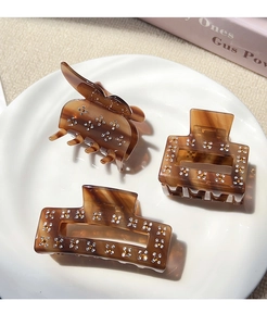 Detailed view of amber acetate hair claw clips with sparkling floral rhinestone patterns
