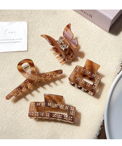 Detailed view of four amber tortoiseshell hair claws with sparkling rhinestone flower patterns