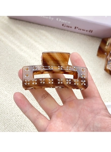 Macro shot of amber leopard acetate hair claw clip with crystal flower detail and rhinestones