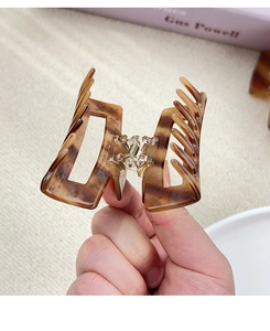 Macro view of a geometric hollow hair claw clip with brown tortoiseshell leopard pattern