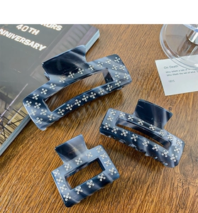 Three-piece set of navy marble acetate hair claws with sparkling rhinestone floral details
