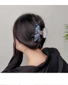 Close-up of smoke blue acetate hair claw clip with star patterns on a ponytail