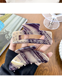 Vue détaillée de pinces à cheveux marbrées avec motifs floraux en strass sur les mains