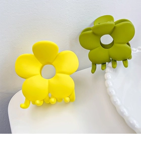 Gros plan de pinces à cheveux fleurs mates en jaune vif et vert olive élégant