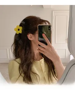 Vue détaillée de la pince à cheveux fleur jaune mate portée par un mannequin