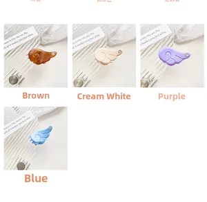 Detail view of mini angel wing hair clips with rhinestones in multiple pastel colors