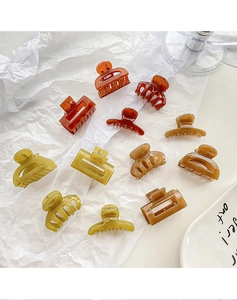 Détail de mini pinces à cheveux assorties aux tons ambre et terre sur fond blanc