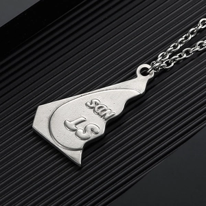 Macro detail of silver geometric pendant with STNDS relief and metal link chain