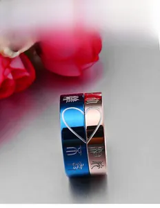 Detail of split heart couple rings with engraved Chinese characters in blue and rose gold