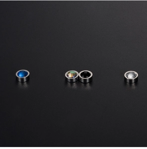 Detail of four colored magnetic stud earrings in blue, rainbow, black and white steel
