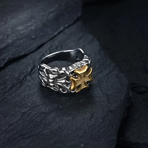 Macro shot of Gothic mens ring with silver floral reliefs and a gold Maltese cross on rock