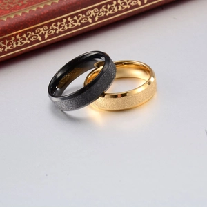 Close-up of black and gold matte titanium steel couple rings with sandblasted finish