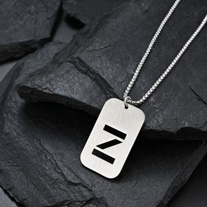 Polished stainless steel dog tag necklace with letter Z pendant on a textured stone