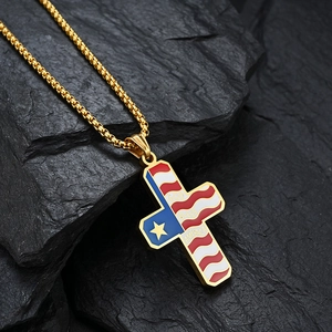 Macro shot of gold cross necklace with American flag enamel and God Bless America engraving