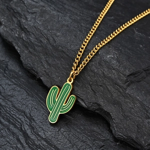 Collana a catena cubana dorata con ciondolo a cactus verde su sfondo di roccia nera