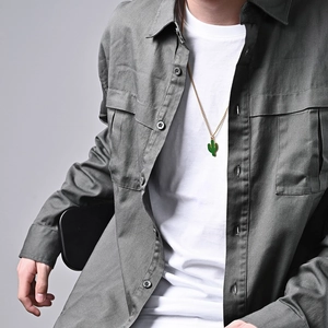Collana dorata con pendente a cactus in smalto verde indossata da modella su camicia grigia