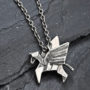 Macro shot of origami Pegasus necklace pendant with geometric facets on dark rock background