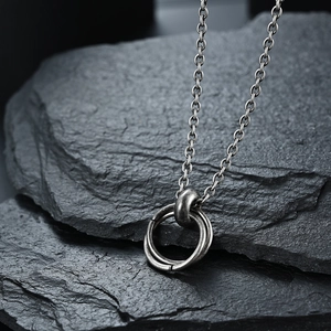 Macro detail of vintage stainless steel double ring pendant on rustic grey stone