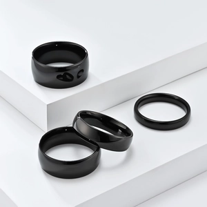 Detail view of four polished black rings in various widths on white geometric steps