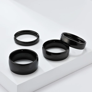 Polished black titanium steel rings in four different widths on minimalist white blocks