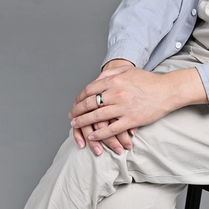 Polished silver minimalist ring shown on index finger against a neutral studio background
