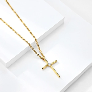Elegant gold cross necklace with crystal pendant on modern geometric display stand
