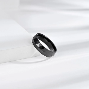 Detail of faceted black ceramic ring with reflective geometric edges and polished finish