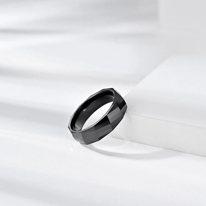 Minimalist black zirconia ceramic ring with geometric diamond-cut facets on white display