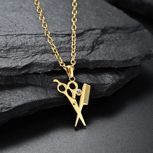 Detailed macro shot of golden scissors and comb pendant with sparkling gemstone accent