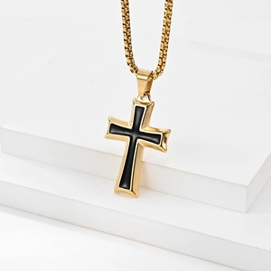 Detail of cross pendant featuring gold stainless steel finish and black enamel inlay