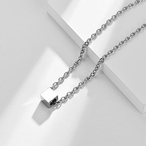 Macro view of minimalist silver titanium steel cube pendant on a cross ring chain