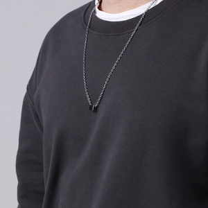 Minimalist stainless steel chain with a small black cube pendant shown on clothing