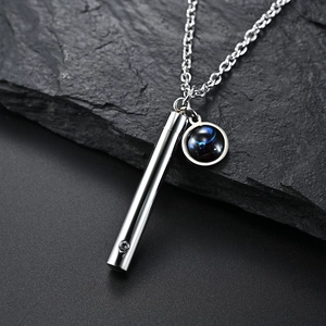 Gros plan d'un pendentif flacon d'huile essentielle zodiaque argenté sur pierre noire