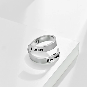 Adjustable stainless steel ring engraved with I am Enough text on white pedestal