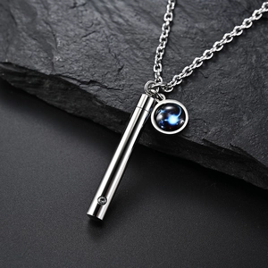 Gros plan d'un collier cylindre en acier inoxydable avec charme zodiacal sur pierre