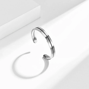 Minimalist silver stainless steel open bangle with black groove line on white geometric cubes