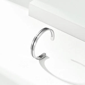 Minimalist polished stainless steel cuff bracelet with black linear inlay on white background
