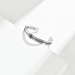 Polished silver stainless steel open bangle with black line detail on geometric stand
